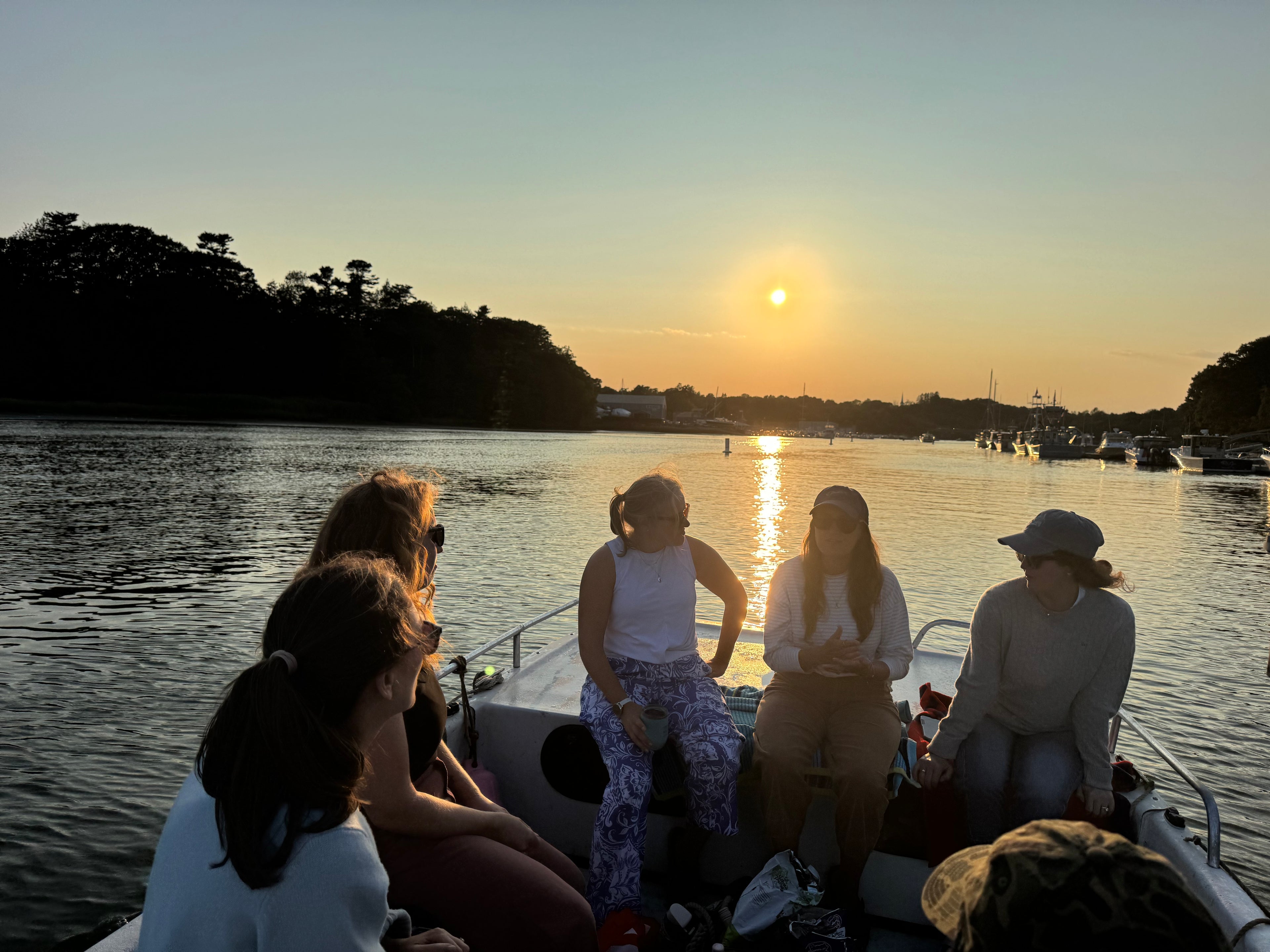 Group of people on a boat enjoying sunset over water